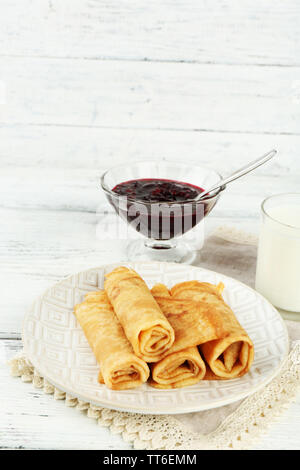 Plateau de crêpes et de confiture de petits fruits dans bol en verre, verre de lait sur fond de bois Banque D'Images