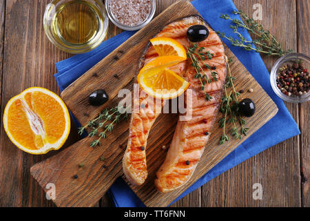 Pavé de saumon et les tranches d'orange sur une planche à découper sur fond de bois Banque D'Images