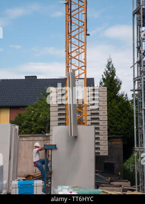 Neuwied, Allemagne - 14 juin 2019 : un travailleur de la construction à l'avant d'une grue soutenant la levée d'un élément préfabriqué Banque D'Images