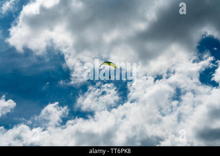 Parapentiste avec un parachute jaune dans un ciel nuageux ciel bleu et lorsqu'il s'approche de sa zone d'atterrissage Banque D'Images