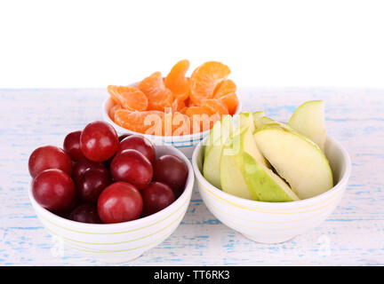 Trois bols de raisins rouges, tranches de pomme et mandarine sur la couleur de la surface en bois isolé sur fond blanc Banque D'Images