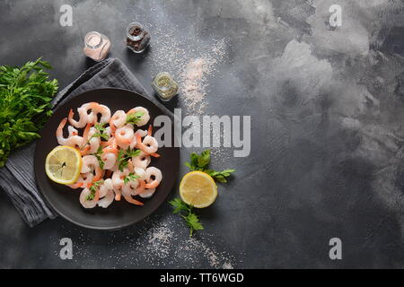 Crevettes fraîches. Matières les crevettes dans une assiette sur un fond sombre. Les fruits de mer. Banque D'Images