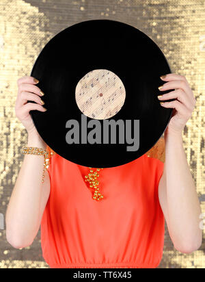 Young woman holding retro record en face de face, sur fond brillant Banque D'Images
