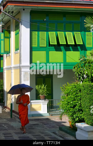 Un moine bouddhiste tenant un parapluie pour abriter du soleil passe Monk's Logements à Prague (Temple de marbre), Bangkok, Thaïlande Banque D'Images