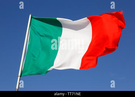Close-up d'un drapeau italien dans le vent isolés contre un ciel bleu. Banque D'Images