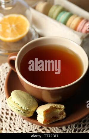 Macarons colorés avec tasse de thé sur fond de bois Banque D'Images