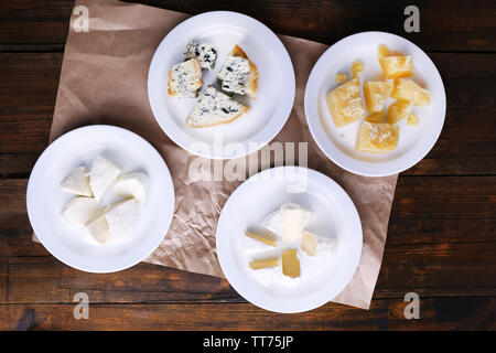 Des plaques de différents types de fromage sur la feuille de papier sur fond de table en bois Banque D'Images