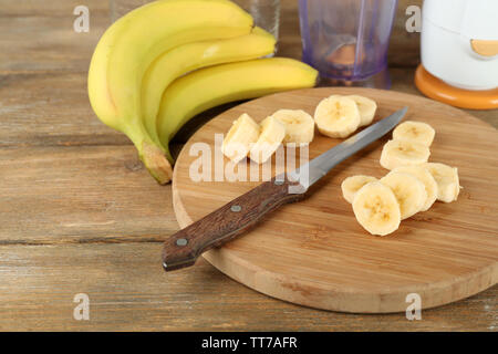 Tranches de banane sur une planche à découper, sur fond de bois Banque D'Images