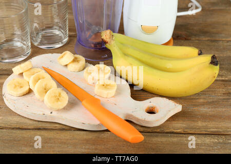 Tranches de banane sur une planche à découper, sur fond de bois Banque D'Images