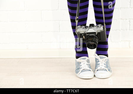 Fille dans sneakers avec retro photo caméra dans la pièce Banque D'Images