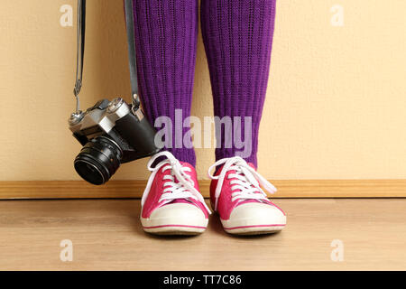 Fille dans sneakers avec retro photo caméra dans la pièce Banque D'Images