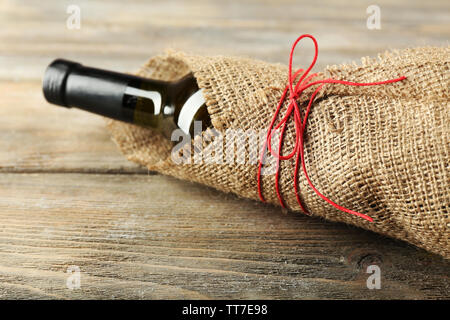 Bouteille de vin emballé dans un tissu de toile de fond sur des planches Banque D'Images