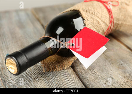 Bouteille de vin emballé dans un tissu de toile de fond sur des planches Banque D'Images
