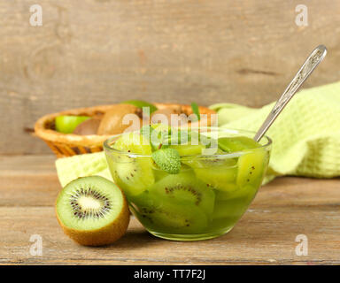 Confiture de kiwis savoureux dans bol en verre sur fond de bois Banque D'Images