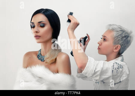 Salon de beauté Cheveux redresse beau modèle sur l'ensemble pendant la pause. Coiffure styling rend une fille avant de prendre des photos Banque D'Images