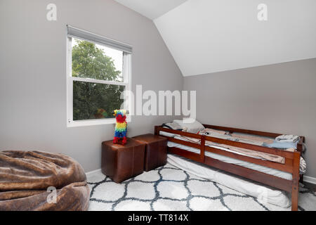 La chambre de l'enfant avec rien sur les murs, un lit simple, fauteuil poire, et un pinata assis sur le dessus de certaines petites chaises. Banque D'Images