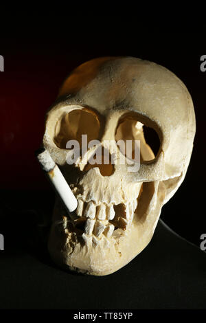 Les fumeurs de cigarettes avec scull dans sa bouche sur fond sombre Banque D'Images