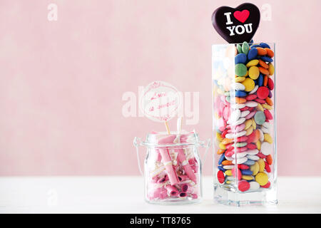 Bonbons colorés avec l'inscription dans un vase sur la table sur un fond de couleur Banque D'Images