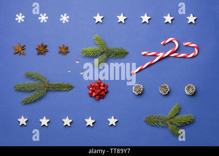 Composition de Noël avec du sucre de cannes, de stars, anis, cônes et branches de sapin sur fond bleu foncé Banque D'Images