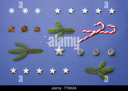 Composition de Noël avec du sucre de cannes, de stars, anis, cônes et branches de sapin sur fond bleu foncé Banque D'Images