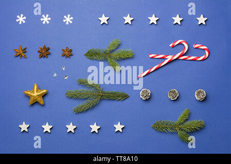 Composition de Noël avec du sucre de cannes, de stars, anis, cônes et branches de sapin sur fond bleu foncé Banque D'Images