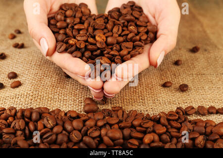 Femmes avec café en grains en forme de coeur sur fond tissu jute Banque D'Images