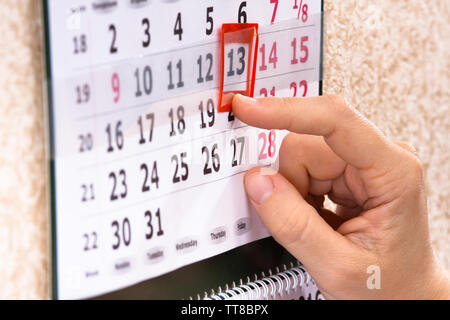 Placer la main femme marque rouge sur la date du calendrier, gros plan Banque D'Images