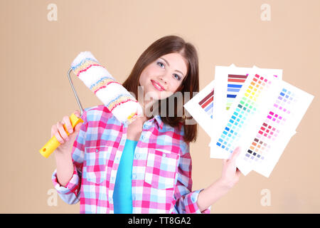 Belle fille avec un rouleau et palette de couleurs près de wall Banque D'Images