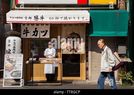 Tokyo, Japon - 18 août 2019 : old asian man marche dans la rue alors que la femme japonaise manager tente d'inviter le client à prendre le petit déjeuner ou le déjeuner Banque D'Images