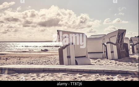 Retro photo stylisée de chaises de plage en osier vide sur une plage au coucher du soleil. Banque D'Images