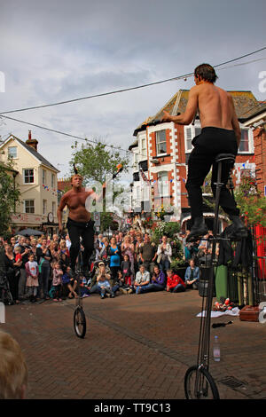 La ville de Sidmouth, Devon, Angleterre - 5 août 2012 : Deux jongleurs et artistes de rue effectuer avec monocycles et fire clubs dans la place de la ville à un apprec Banque D'Images