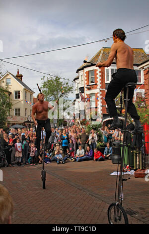 La ville de Sidmouth, Devon, Angleterre - 5 août 2012 : Deux jongleurs et artistes de rue effectuer avec monocycles et fire clubs dans la place de la ville à un apprec Banque D'Images