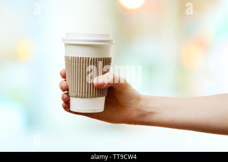 Hand holding paper cup de café sur fond lumineux Banque D'Images