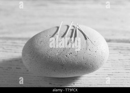 Les aiguilles d'Acupuncture sur spa pierre sur table en bois, gros plan Banque D'Images