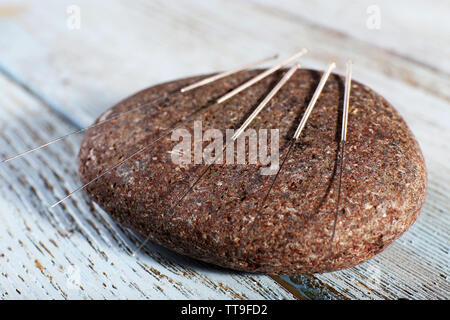 Les aiguilles d'Acupuncture sur spa pierre sur table en bois, gros plan Banque D'Images