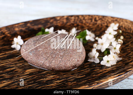 Les aiguilles d'Acupuncture sur plaque de bois avec galets et rameau en fleurs, gros plan Banque D'Images