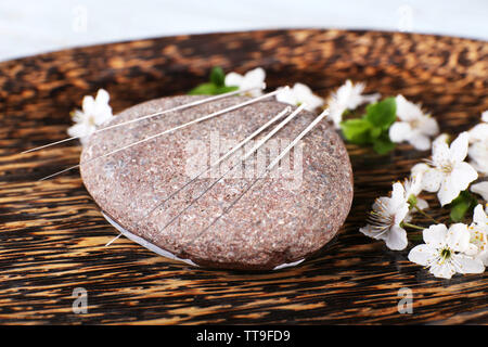 Les aiguilles d'Acupuncture sur plaque de bois avec galets et rameau en fleurs, gros plan Banque D'Images