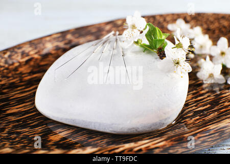 Les aiguilles d'Acupuncture sur plaque de bois avec galets et rameau en fleurs, gros plan Banque D'Images