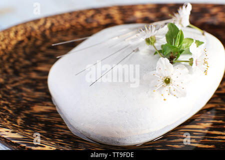 Les aiguilles d'Acupuncture sur plaque de bois avec galets et rameau en fleurs, gros plan Banque D'Images