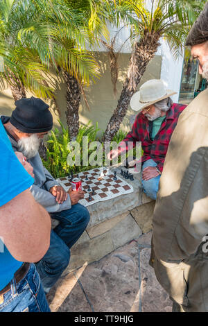 Un homme de race blanche âgés est titulaire d'un signe les personnes difficiles à un jeu d'échecs. Il a son conseil d'échecs mis en place prêt à jouer sur un muret en pierre. Banque D'Images