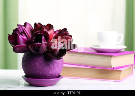 Magnifiques tulipes en pot avec des livres sur fond de tissu Banque D'Images