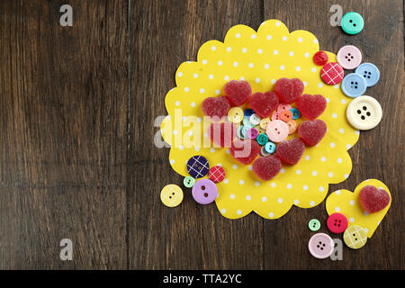 Gummy candies disposés en forme de coeur avec des boutons sur la table close up Banque D'Images