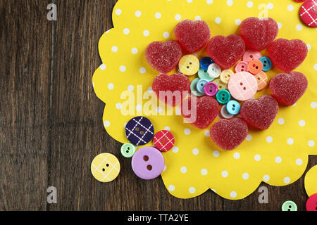 Gummy candies disposés en forme de coeur avec des boutons sur la table close up Banque D'Images