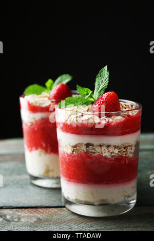 Dessert avec des fraises fraîches, crème et granola, sur une table en bois, sur fond sombre Banque D'Images