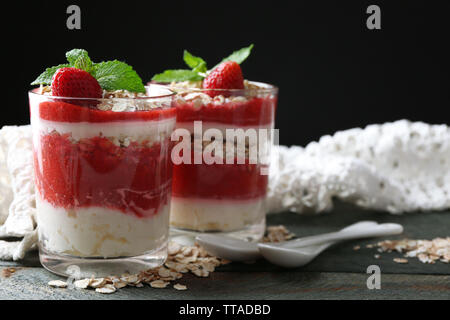 Dessert avec des fraises fraîches, crème et granola, sur une table en bois, sur fond sombre Banque D'Images