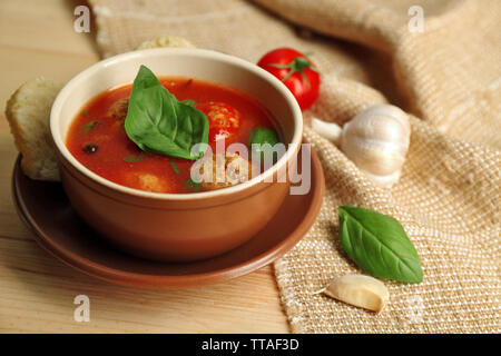 Soupe de tomate avec les boulettes de viande sur la cuillère en bois sur fond de bois Banque D'Images