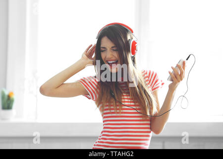 Woman listening music casque en arrière-plan on windowsill Banque D'Images