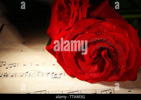 Belles roses rouges sur les feuilles de musique, gros plan Banque D'Images