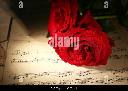 Belles roses rouges sur les feuilles de musique, gros plan Banque D'Images