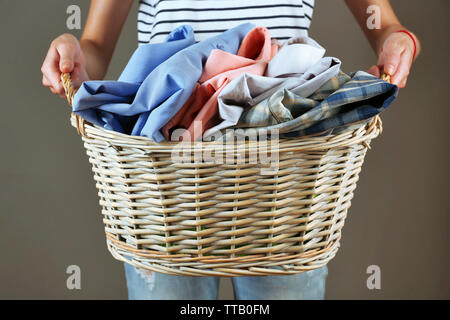 Woman holding basket avec des vêtements sur fond gris Banque D'Images